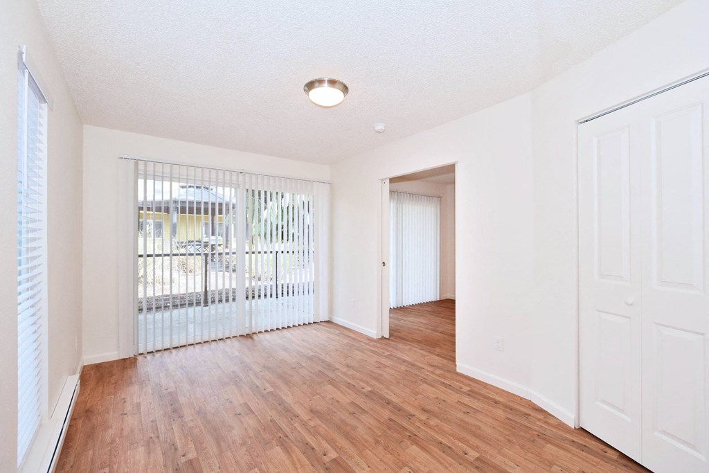 an empty living room with wood flooring and a door to a balcony
