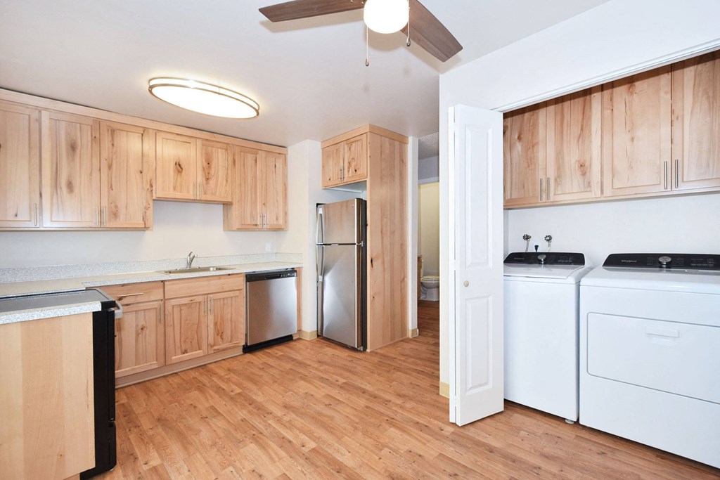 an empty kitchen with white appliances and wooden cabinets