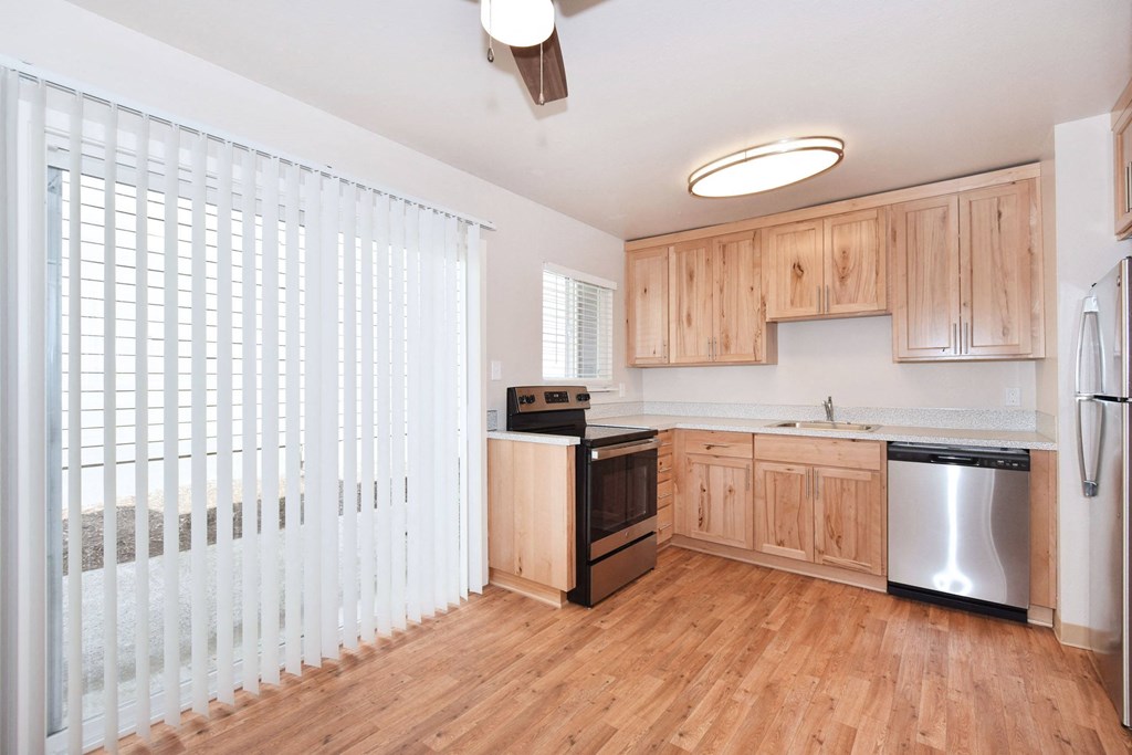 an empty kitchen with wood floors and wooden cabinets and a large window