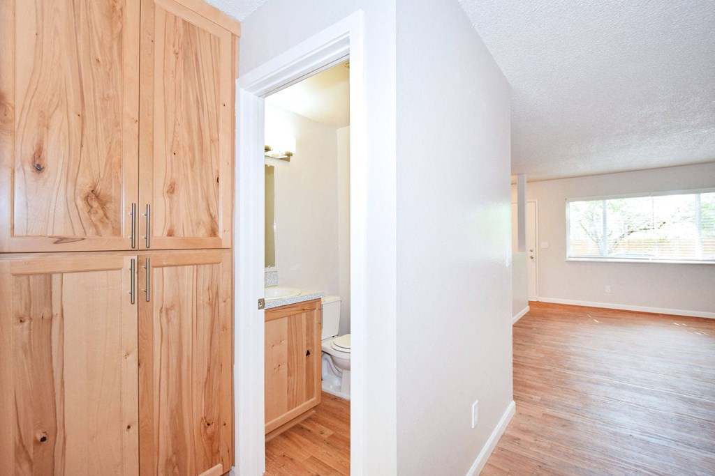 an empty living room and a bathroom with wood flooring
