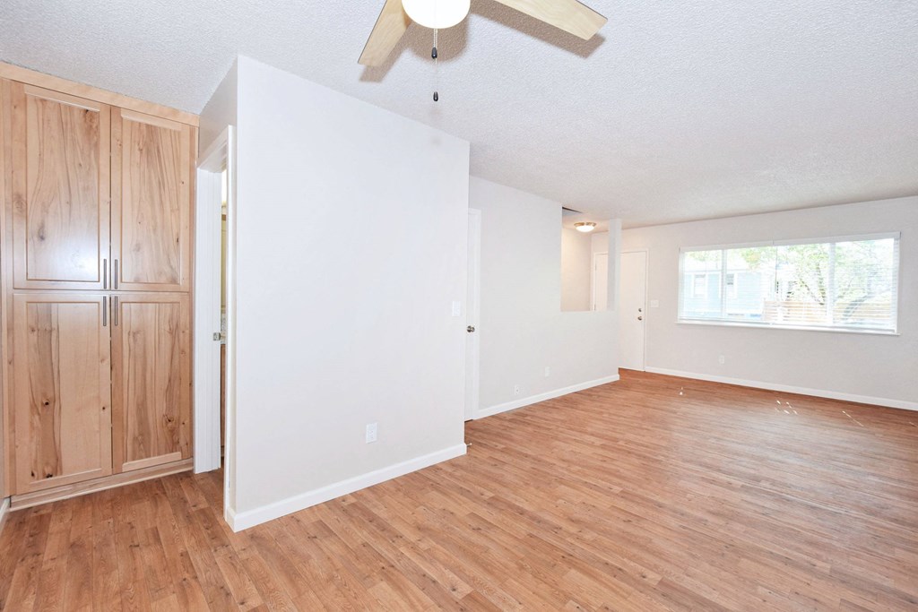 an empty living room with wood floors and a ceiling fan