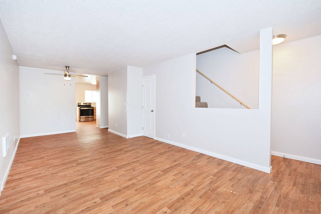 an empty living room with wood floors and white walls