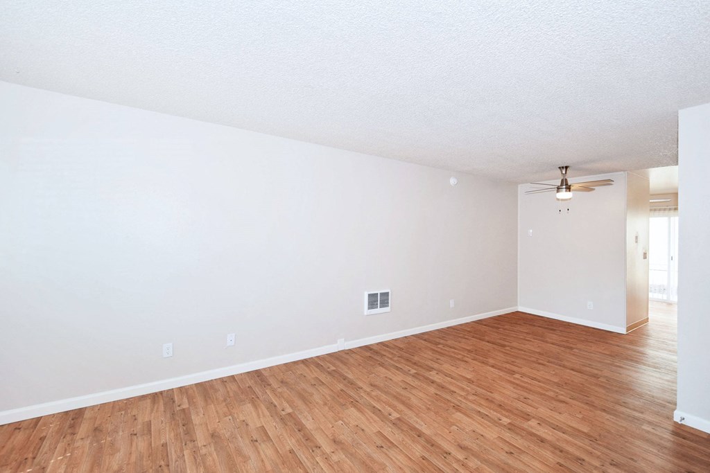 the spacious living room with hardwood floors and white walls