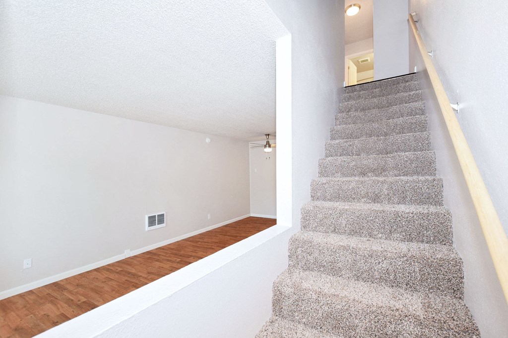 the living room and staircase of a house with a carpeted floor and white walls