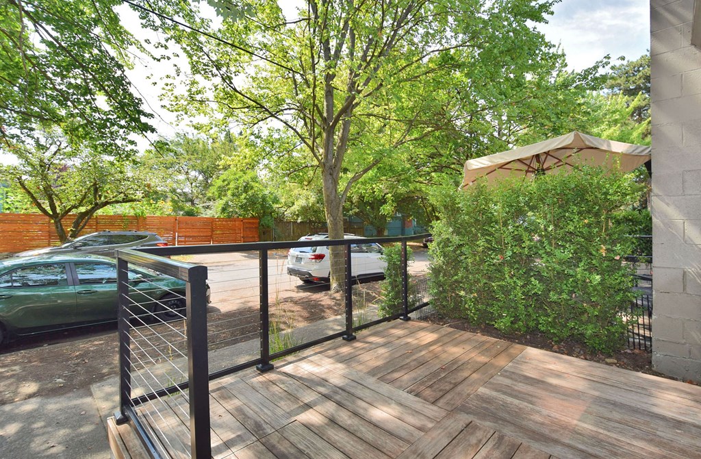 a porch with a fence and a tree and a parking lot