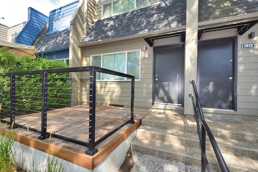 the front of a house with a wooden deck and two doors
