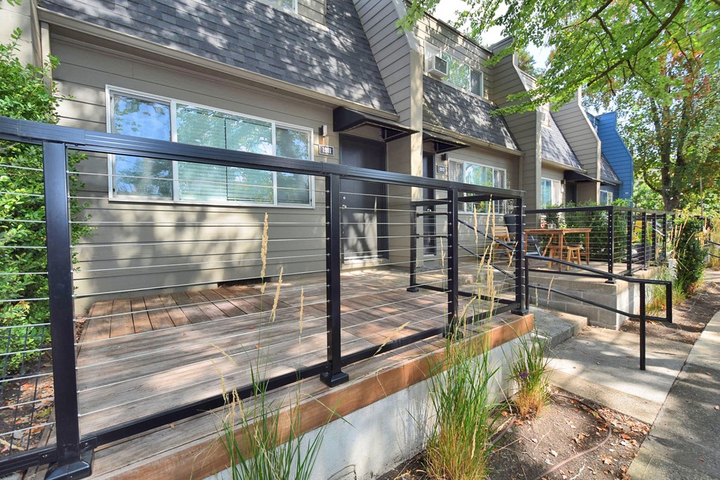 a deck with a black railing in front of a house