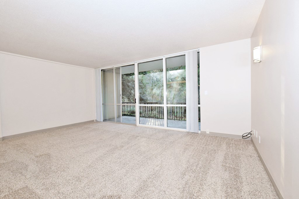 an empty living room with sliding glass doors to a balcony