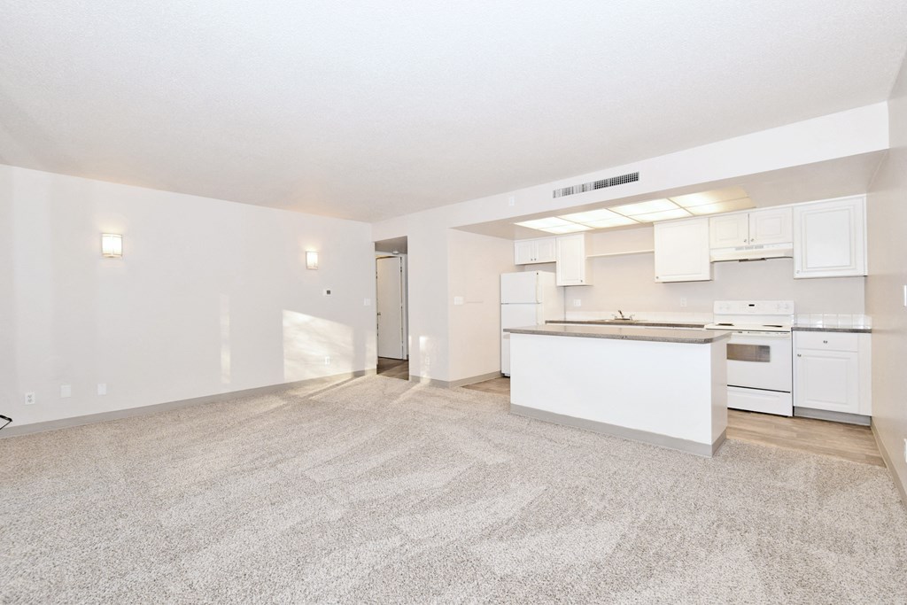 the living room and kitchen of an apartment with white cabinets and white appliances