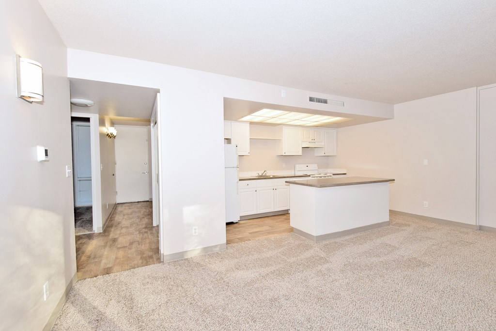 the living room and kitchen of an apartment with white cabinets and a white kitchen island