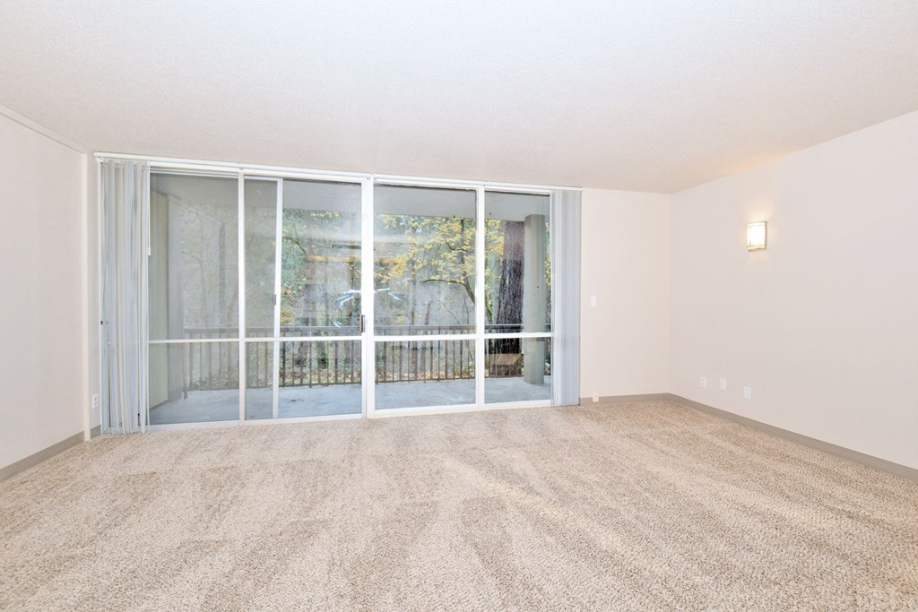an empty living room with glass doors to a balcony