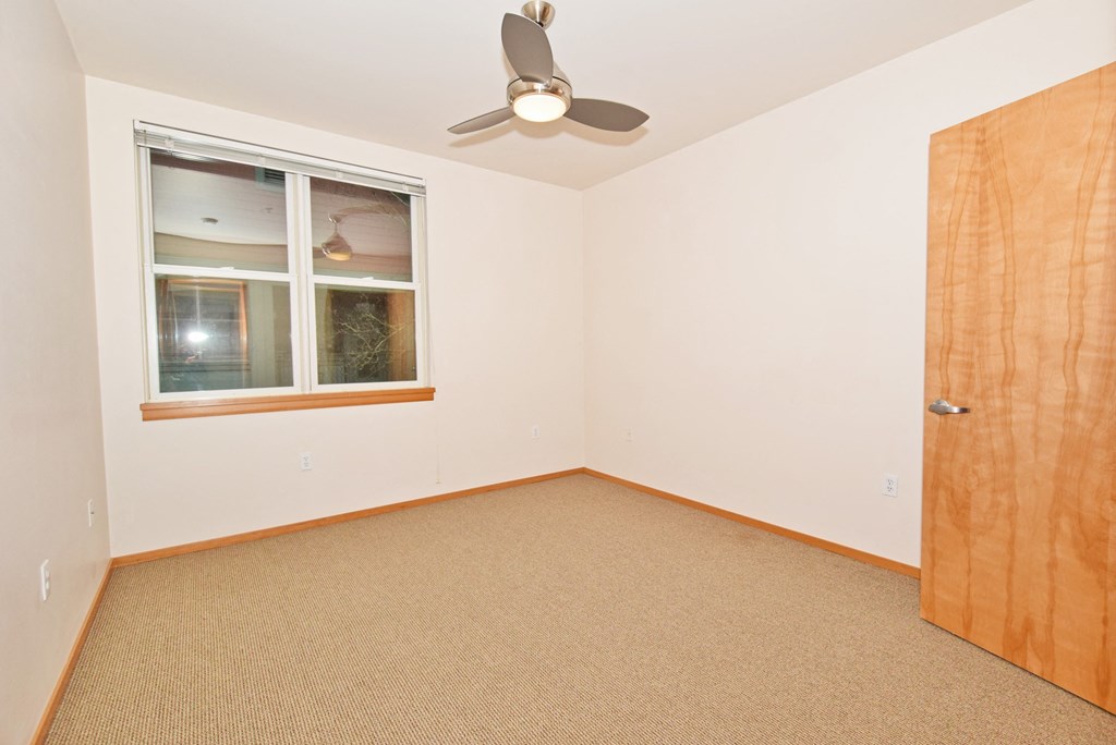 an empty room with a ceiling fan and a window