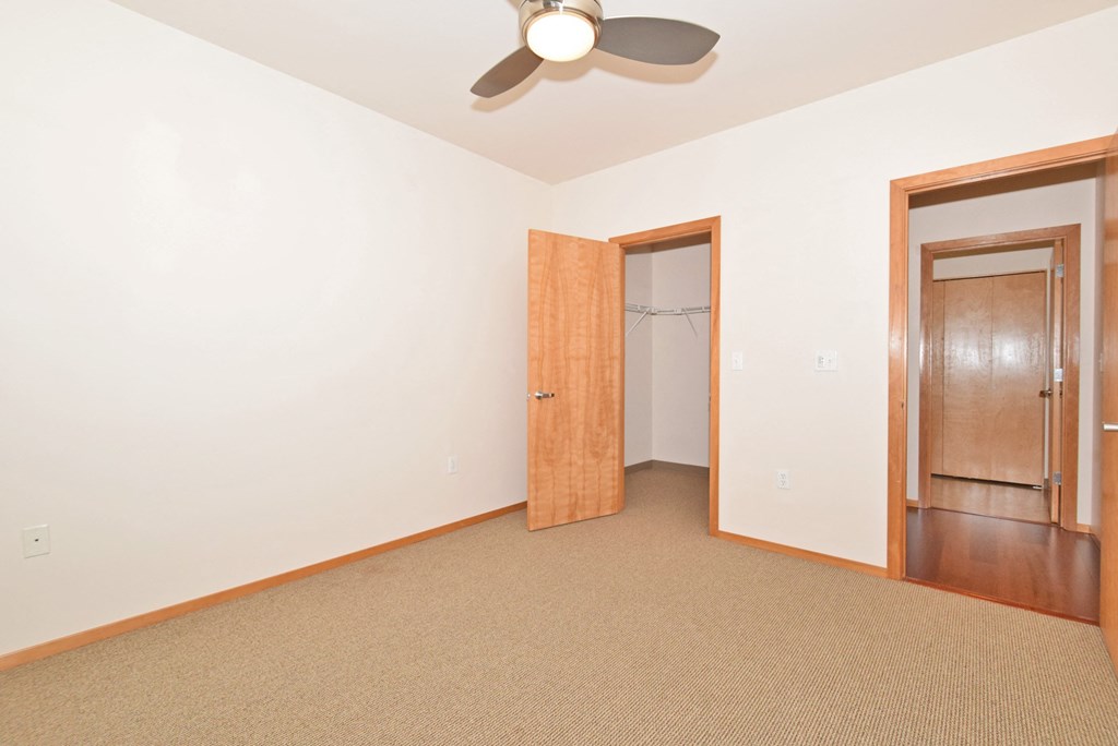 a bedroom with a ceiling fan and a door to a closet