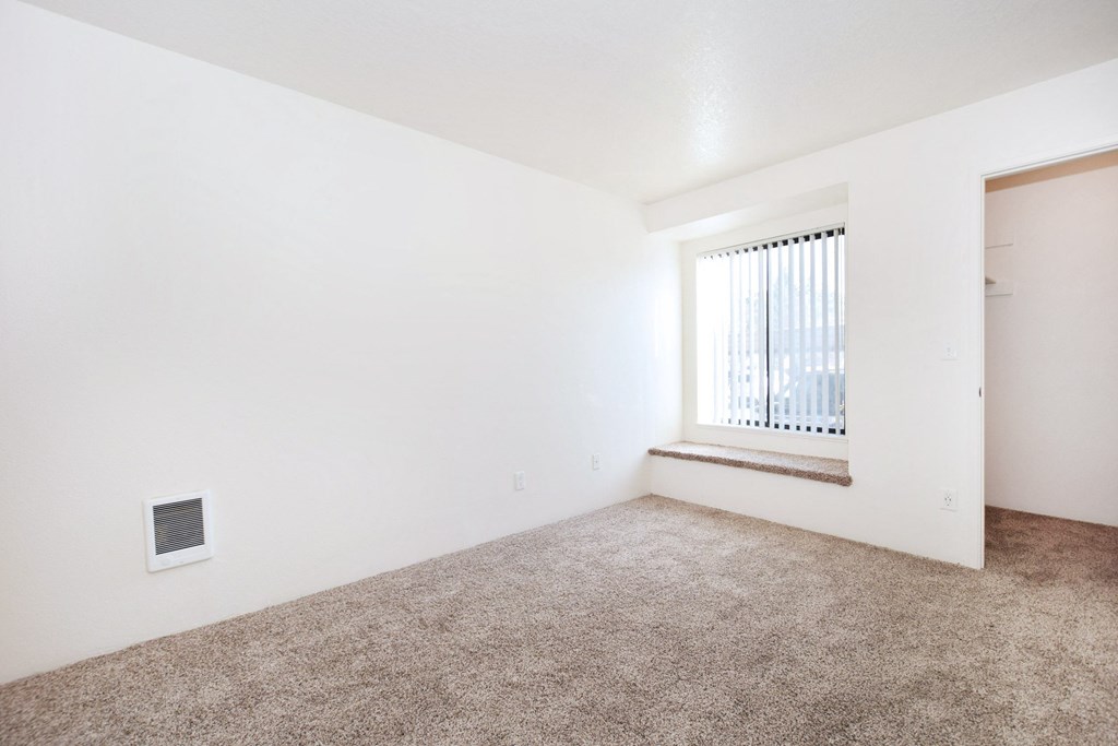 an empty room with a window and carpet