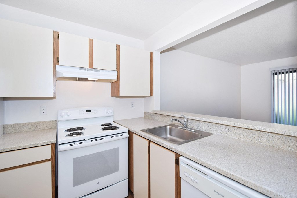 an empty kitchen with white appliances and a sink