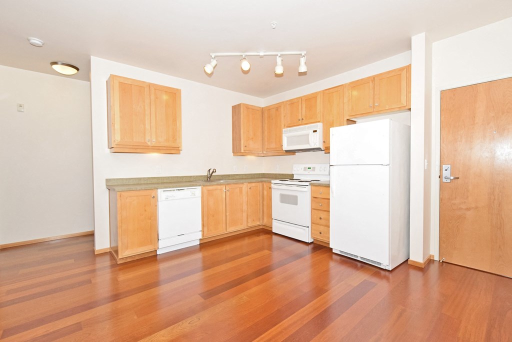 an empty kitchen with wood floors and white appliances