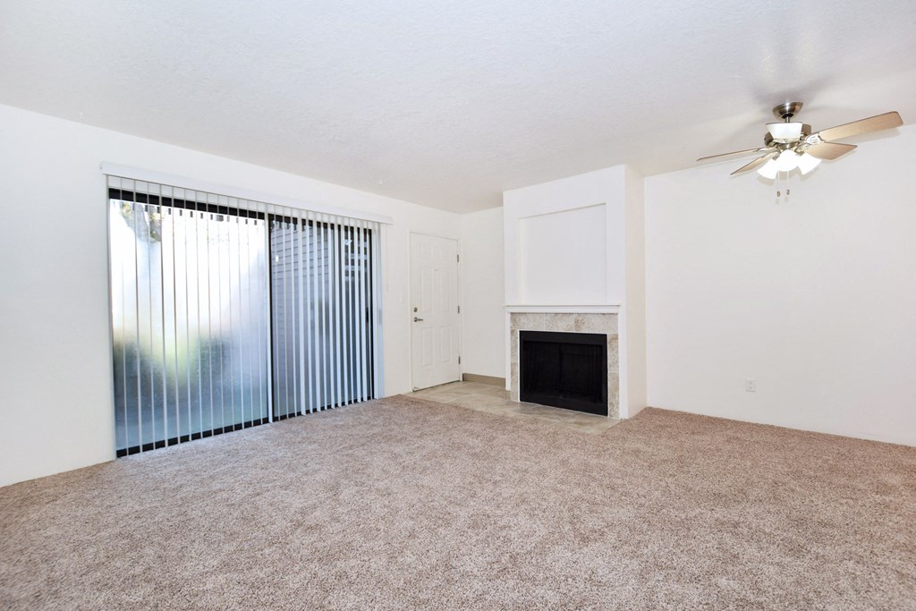 an empty living room with a fireplace and a ceiling fan