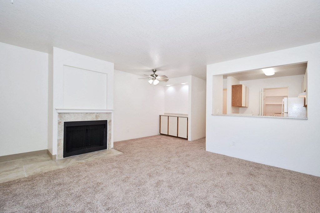 an empty living room with a fireplace and a ceiling fan