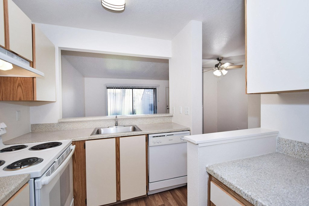 an empty kitchen with white appliances and a window