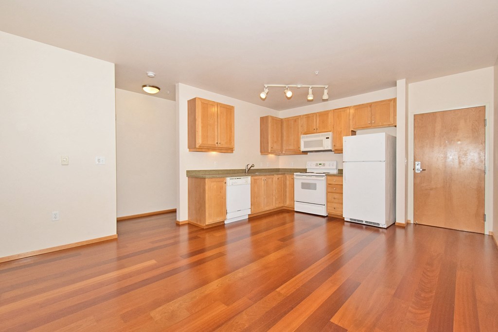 an empty kitchen with wood flooring and white appliances
