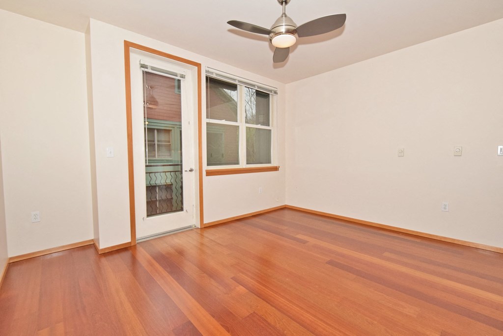 an empty living room with wood floors and a door to a balcony