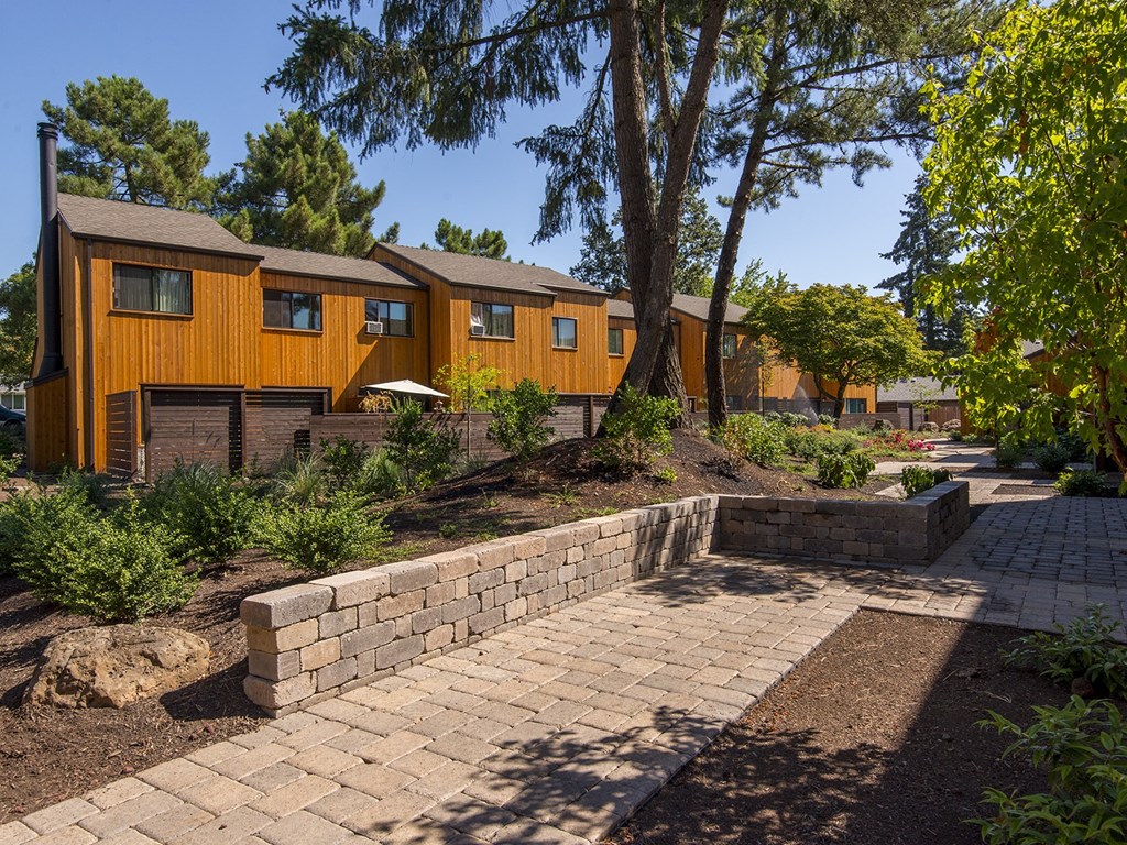 a brick walkway leading up to a house with trees and a courtyard
