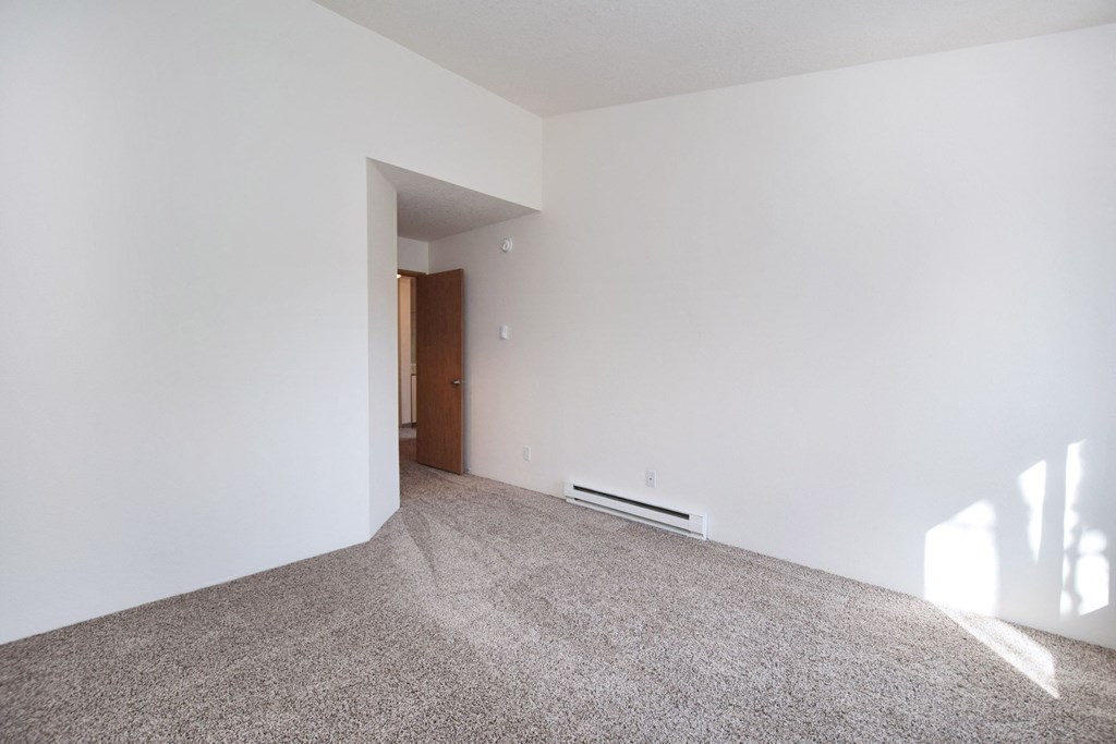 an empty living room with white walls and carpet