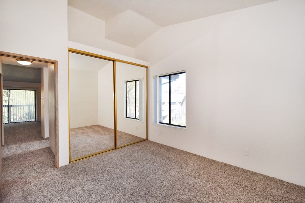 the living room and dining room of a house with white walls and carpet
