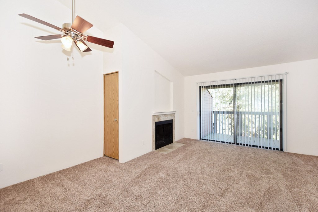 an empty living room with a fireplace and a ceiling fan
