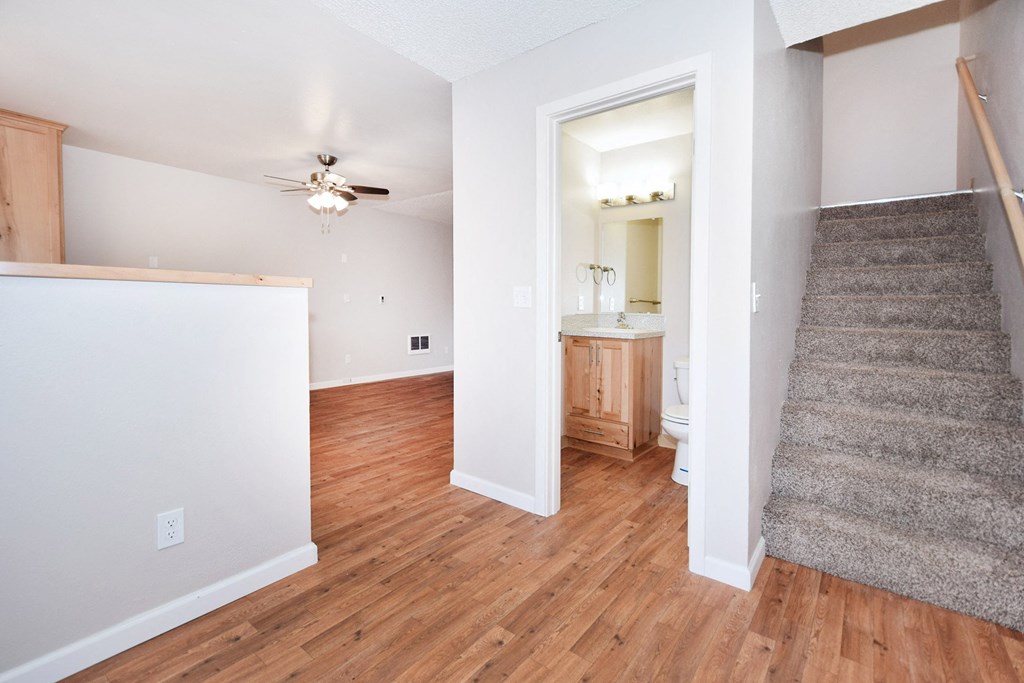 an empty living room with hardwood flooring and a ceiling fan