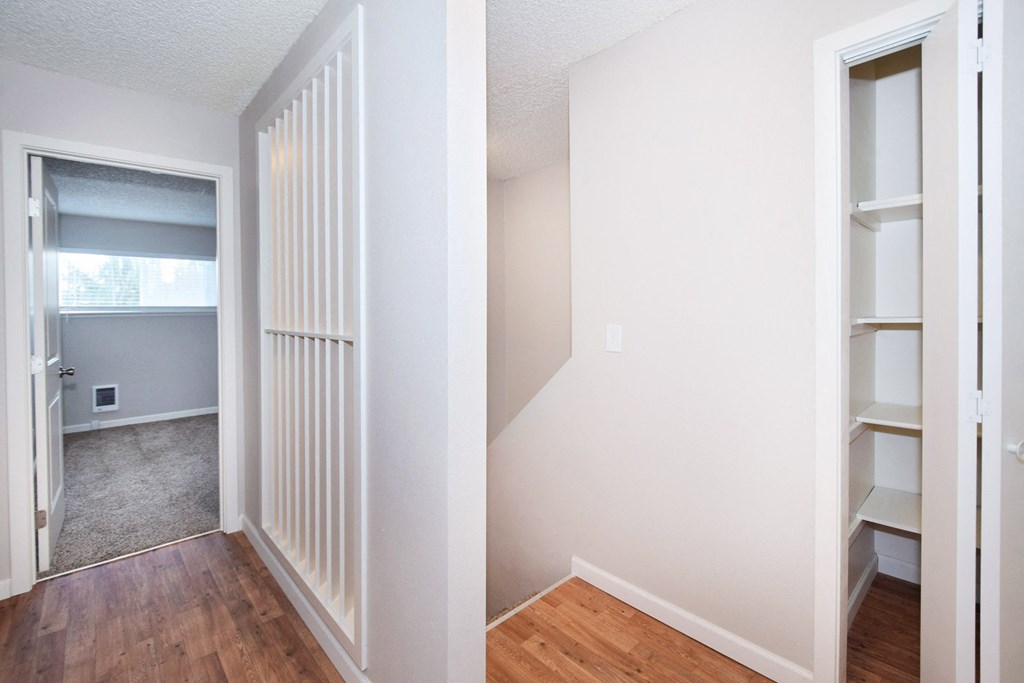 an empty room with a closet and an open door to a room with wood floors