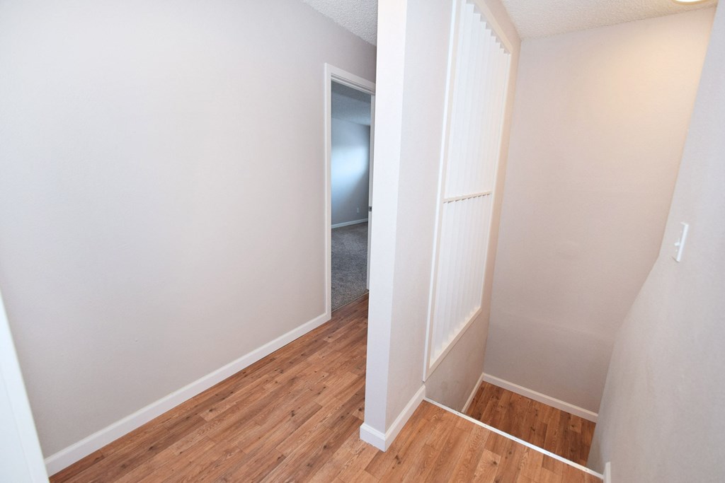 an empty room with wood flooring and a hallway to a closet