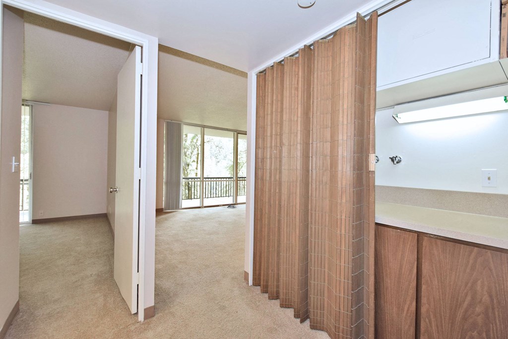 an empty living room with a sliding glass door to a bathroom