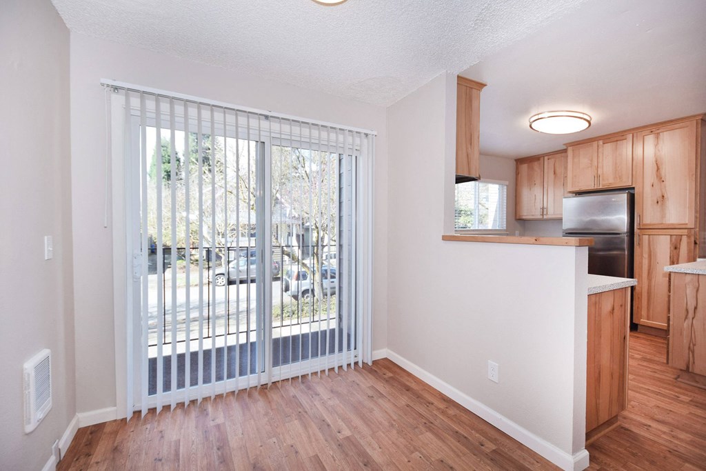 an empty living room with a sliding glass door to a balcony