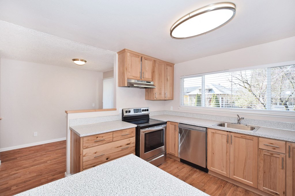 an empty kitchen with wooden cabinets and a window