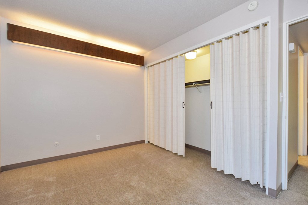 a living room with white curtains and a door to a closet