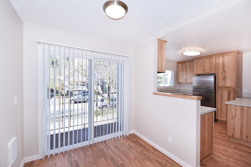 an empty living room with a door to a kitchen