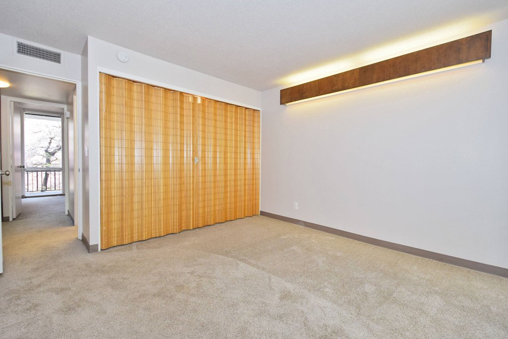 an empty living room with a wooden closet in the corner