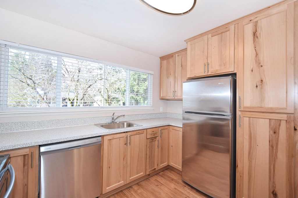a kitchen with wooden cabinets and a stainless steel refrigerator