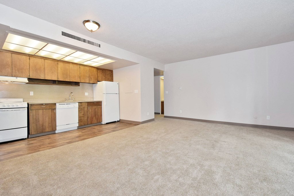 the spacious living room and kitchen with white appliances and wood cabinets