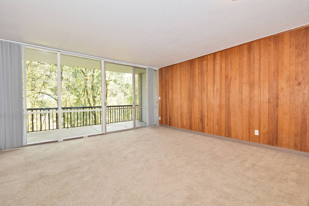 an empty living room with wood paneling and a balcony
