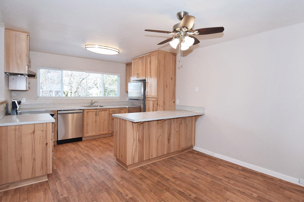 an empty kitchen with wooden cabinets and a ceiling fan