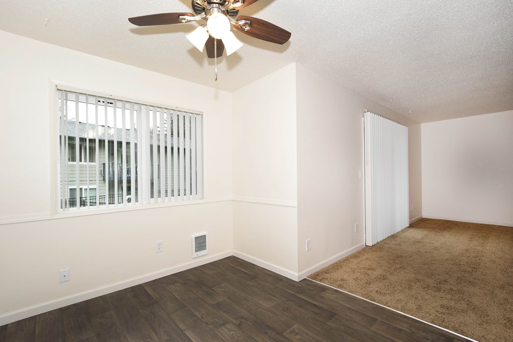 A room with a ceiling fan and a window with blinds.