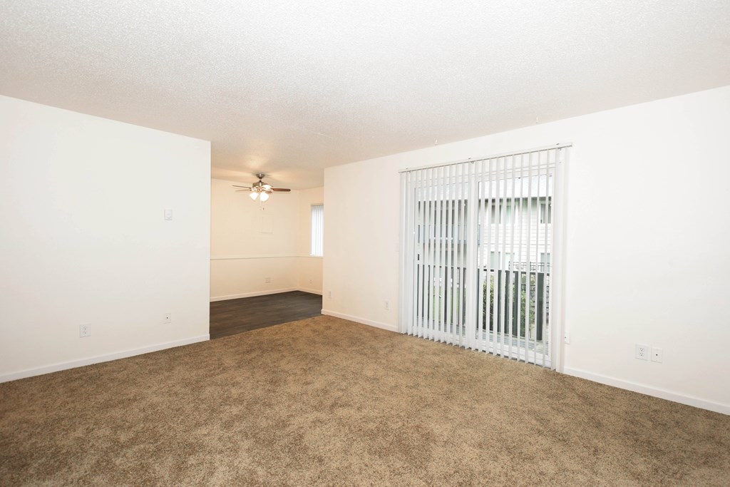 A room with a ceiling fan and a window with blinds.