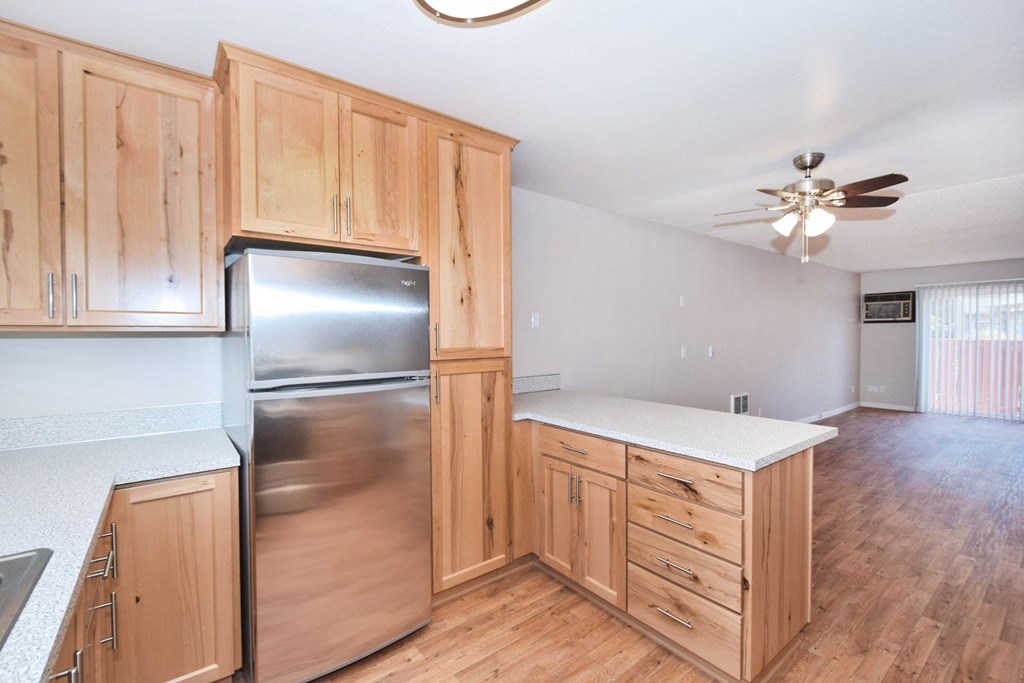 an empty kitchen with wooden cabinets and a stainless steel refrigerator