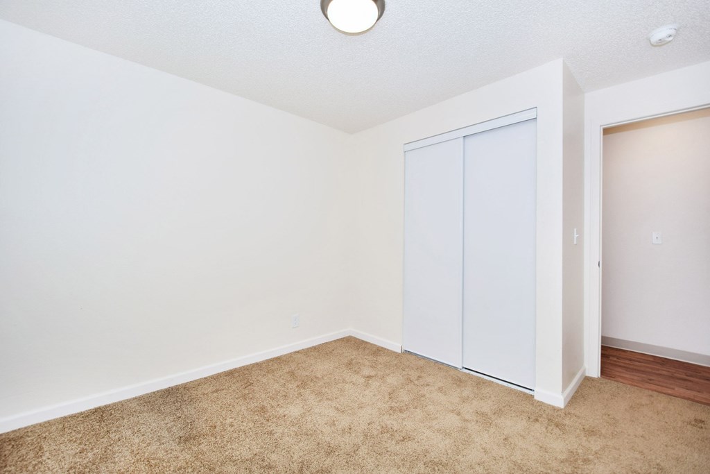 an empty room with white walls and a door to a closet