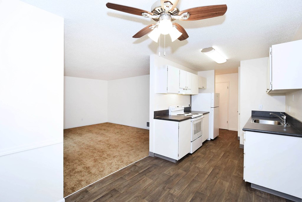 A kitchen with white cabinets and a wood floor.