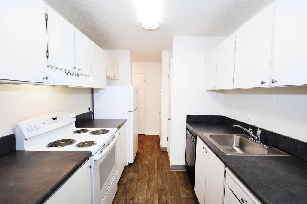 A kitchen with white cabinets and a black countertop.