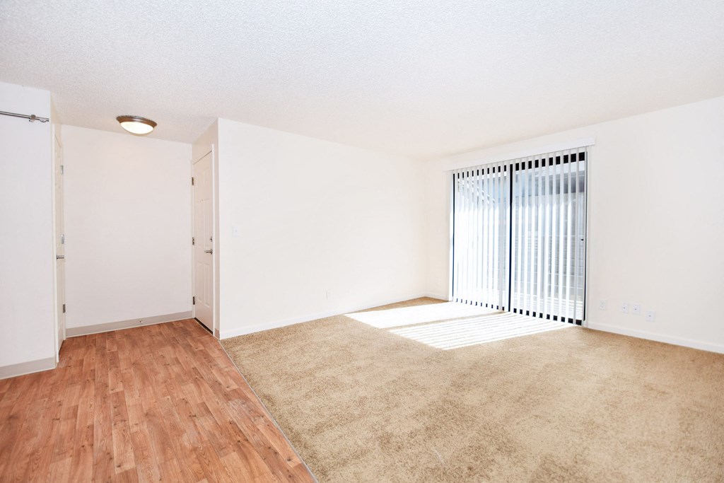 an empty living room with a large window and wood flooring