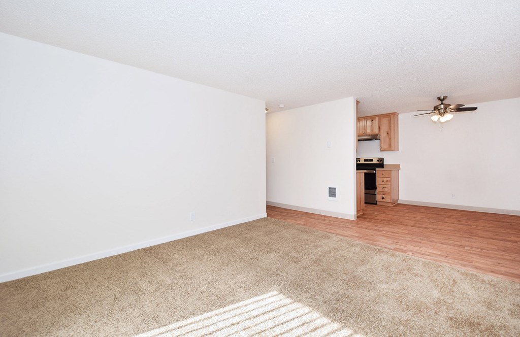 an empty living room with a hard wood floor and a ceiling fan
